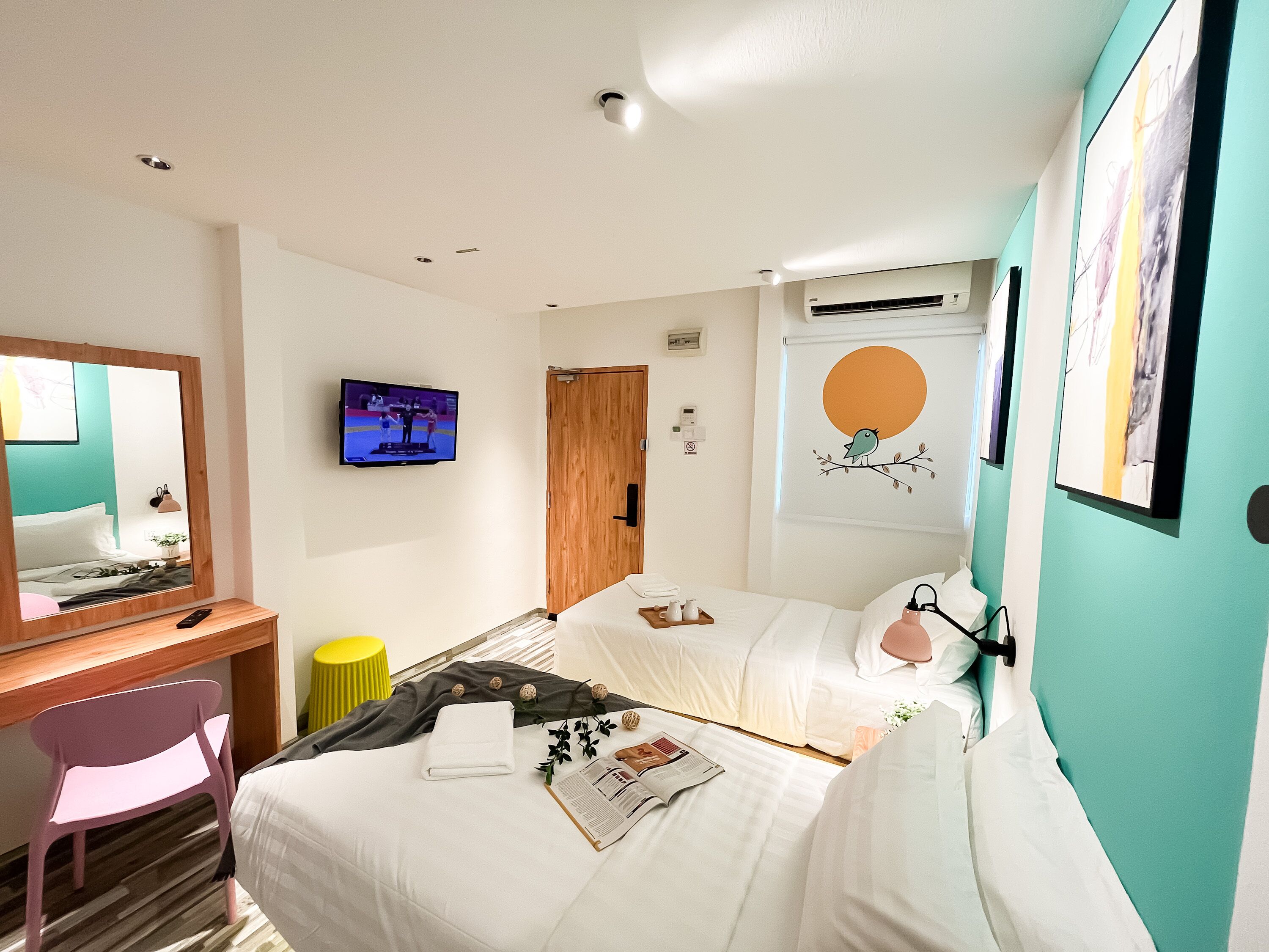 A hotel room with a bed, a desk with a chair, a television, and artwork on the walls.