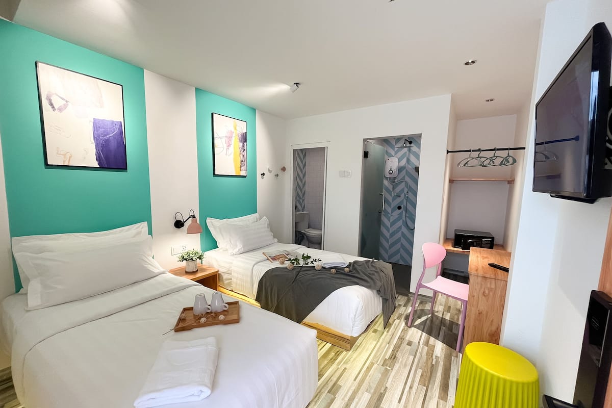 A hotel room with two beds, a bathroom, and a TV.