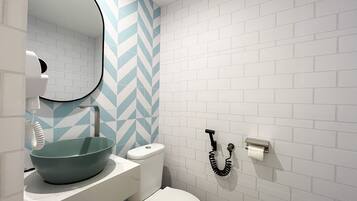 Un baño con inodoro blanco, lavabo con recipiente azul y espejo.