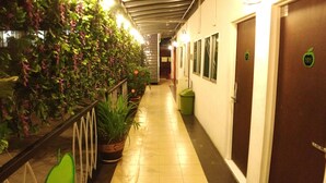 A hallway with a green plant wall, a trash bin, and doors numbered 101 and 102. - Apple 1 Hotel Gurney (George Town)