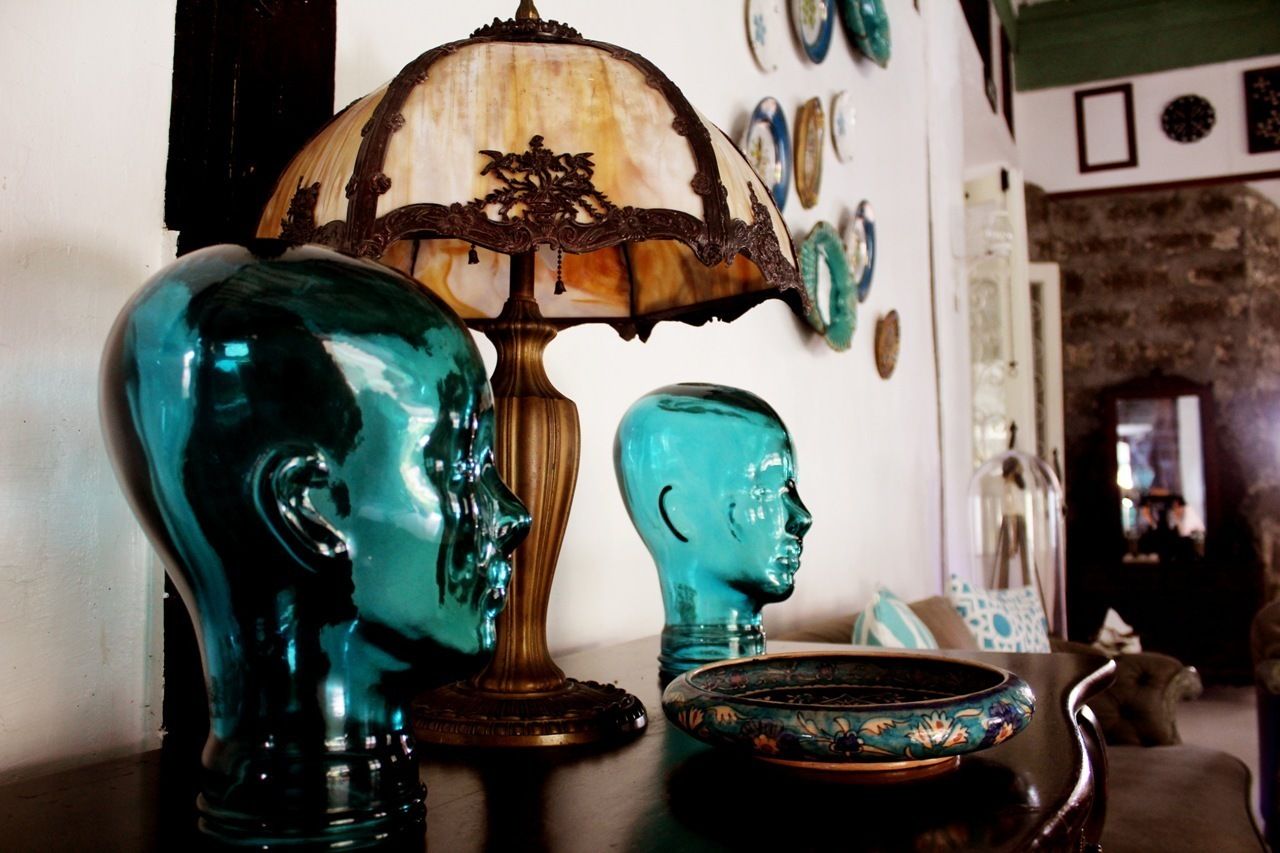A room with a lamp, two glass head-shaped vases, and a decorative plate on a table.