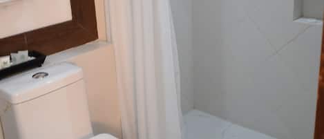 Un baño con inodoro, cortina de ducha y piso de baldosas.