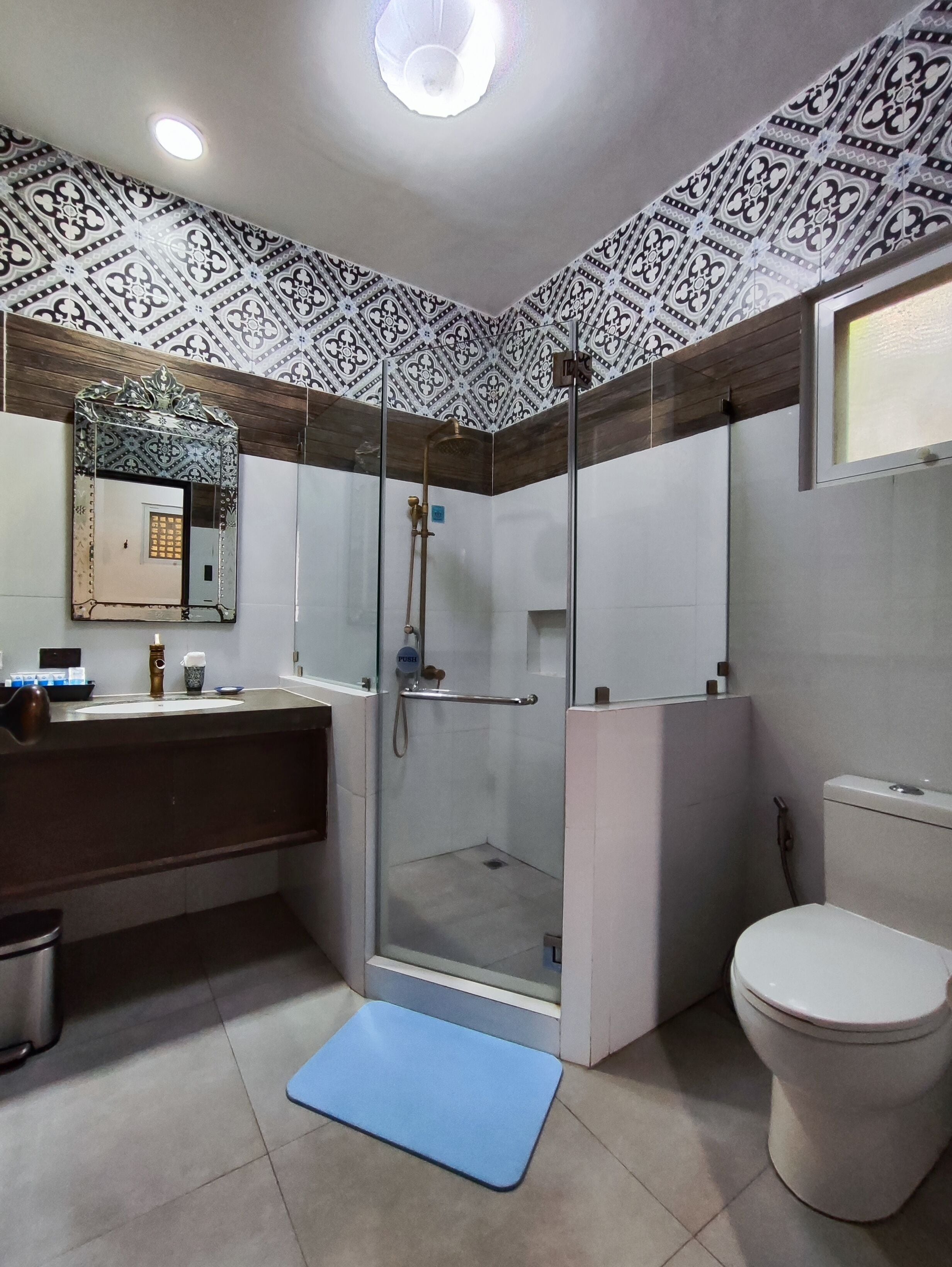 A modern bathroom with a glass-enclosed shower, a toilet, and a sink with a mirror above.