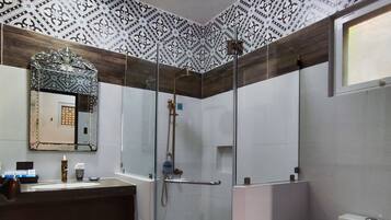 A modern bathroom with a glass-enclosed shower, a toilet, and a sink with a mirror above.
