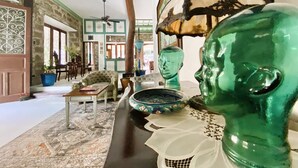 A room with a rustic aesthetic, featuring exposed brick walls, a wooden ceiling, and a mix of traditional and modern furniture. There is a large green vase and a decorative head sculpture on a table. - Paradores Del Castillo (Taal)