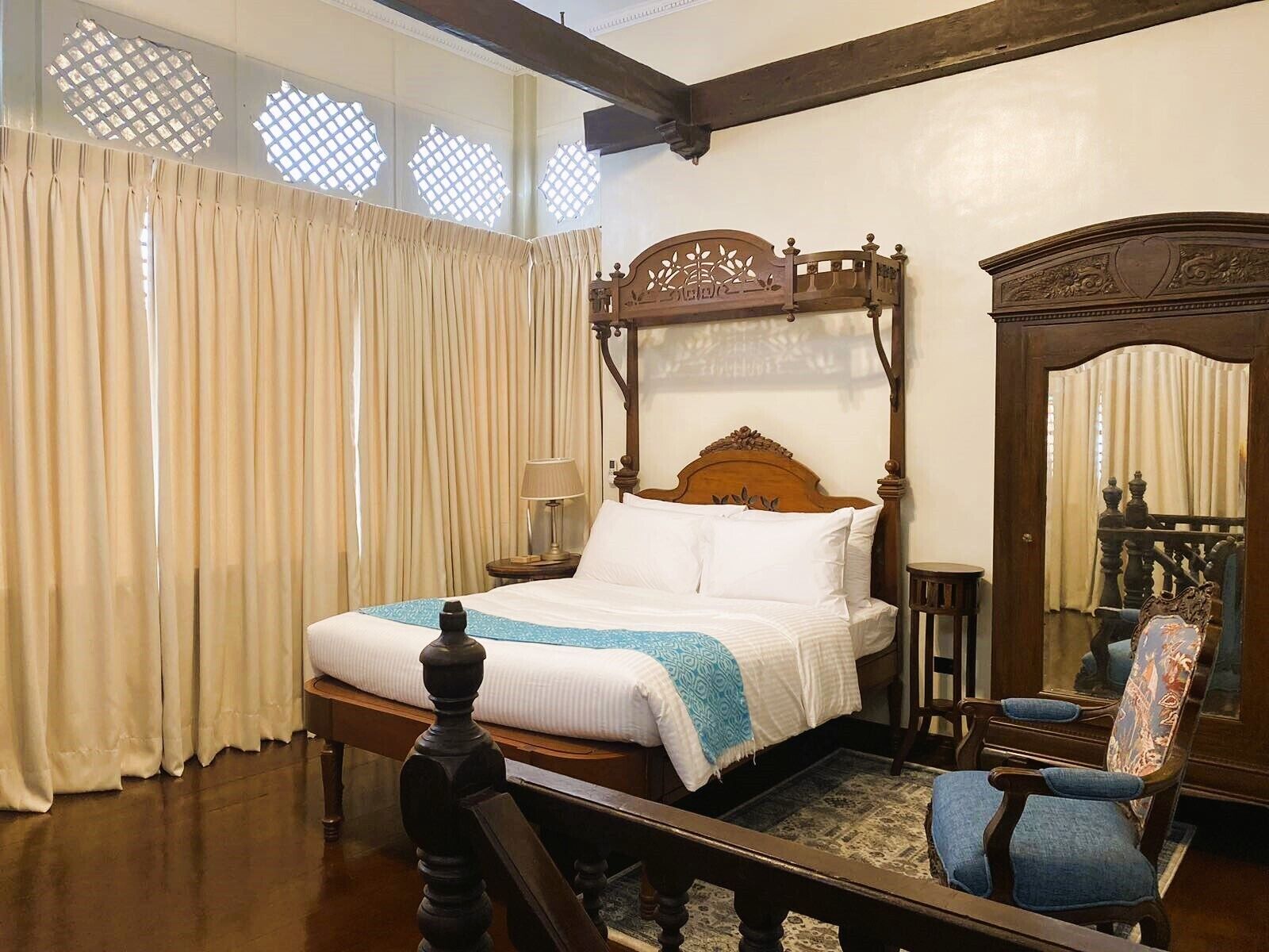 Una camera da letto tradizionale con un letto a baldacchino, una sedia di legno e uno specchio.