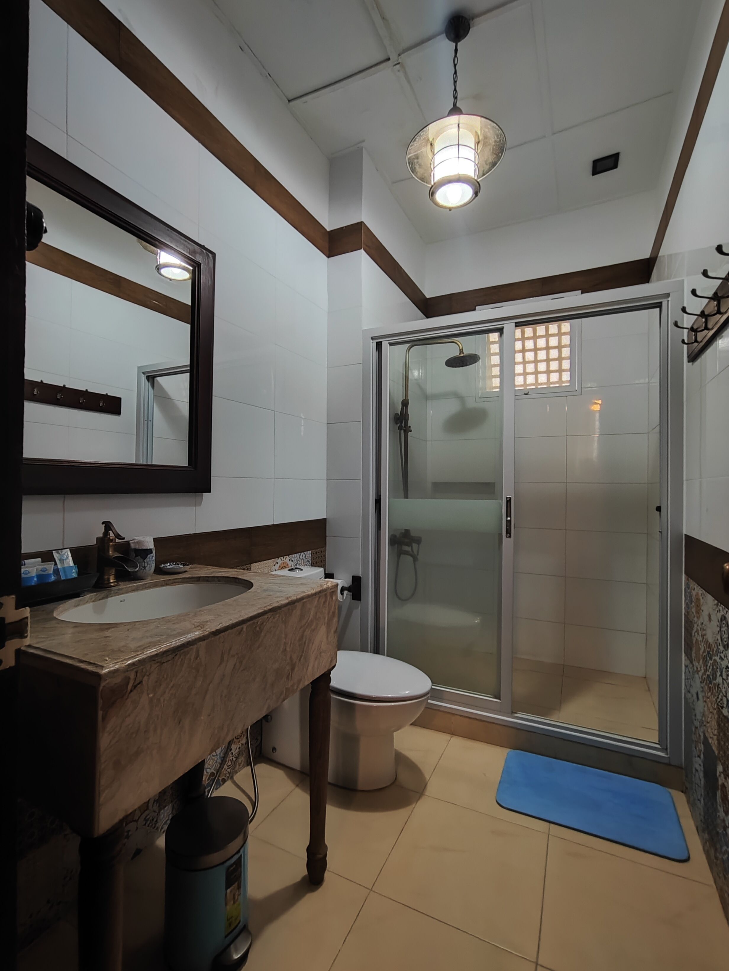 Un baño con un espejo grande, dos lavamanos, un inodoro y una ducha con mampara de vidrio.