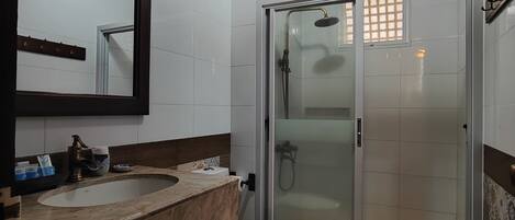 Un baño con un espejo grande, dos lavamanos, un inodoro y una ducha con mampara de vidrio.