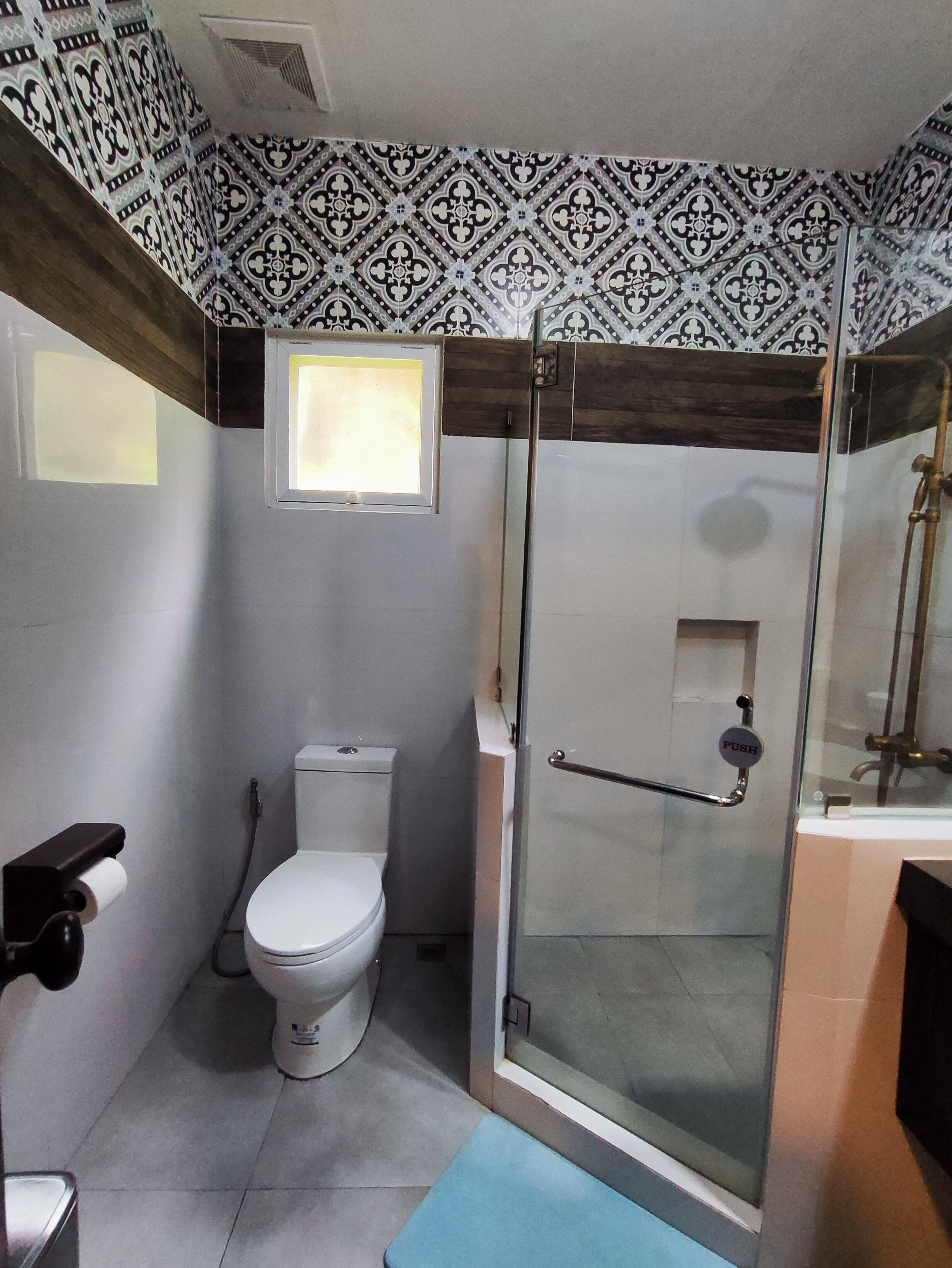 Un baño con inodoro, cabina de ducha de vidrio y ventana.
