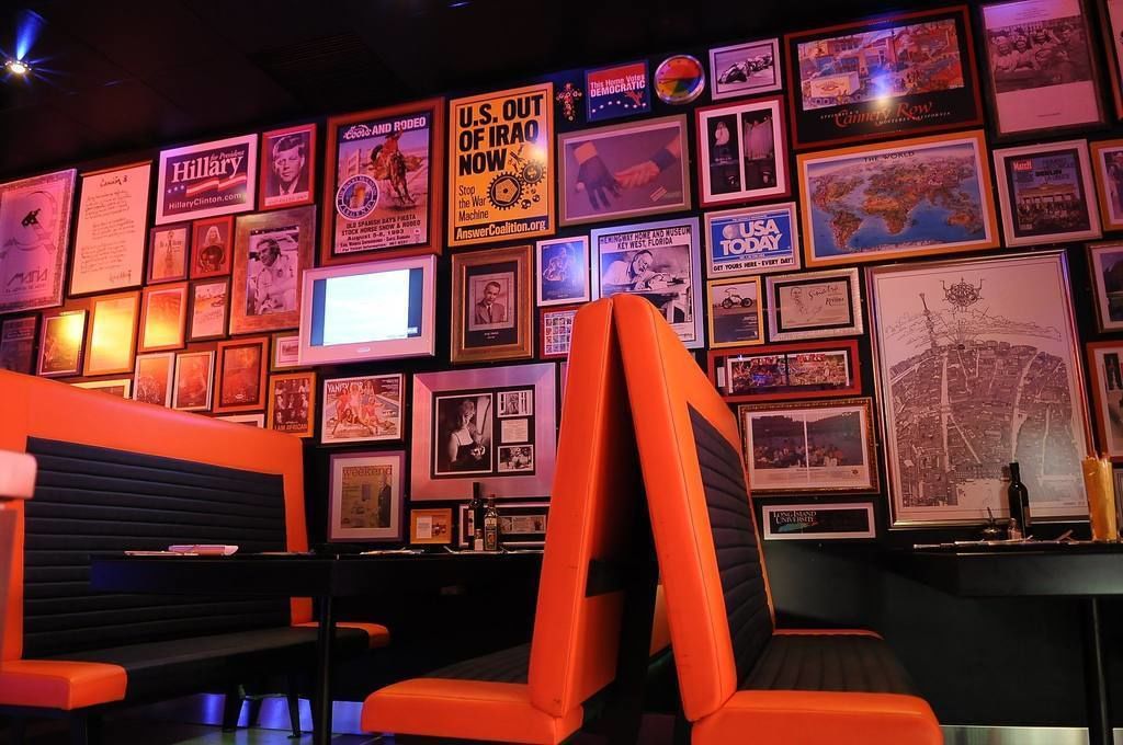 A bar area with orange seating and a wall decorated with framed pictures and posters.