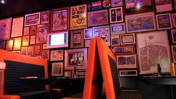 A bar area with orange seating and a wall decorated with framed pictures and posters.