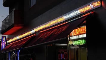 Un edificio con un letrero de neón que dice 'Pizza' y 'Abierto', señalando que está abierto.