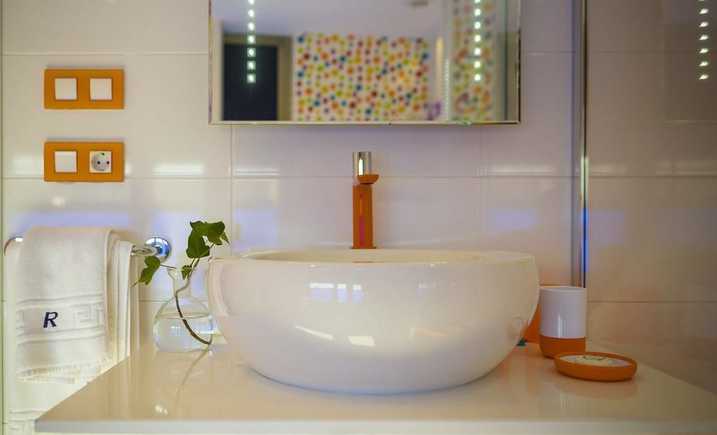 Une salle de bain avec un grand lavabo blanc, un miroir et un porte-serviettes.