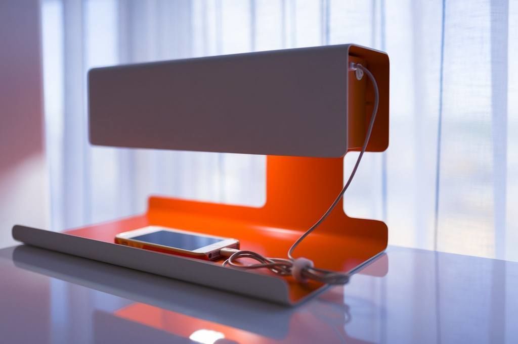 Uma luminária de mesa moderna com um smartphone sobre uma superfície refletora.