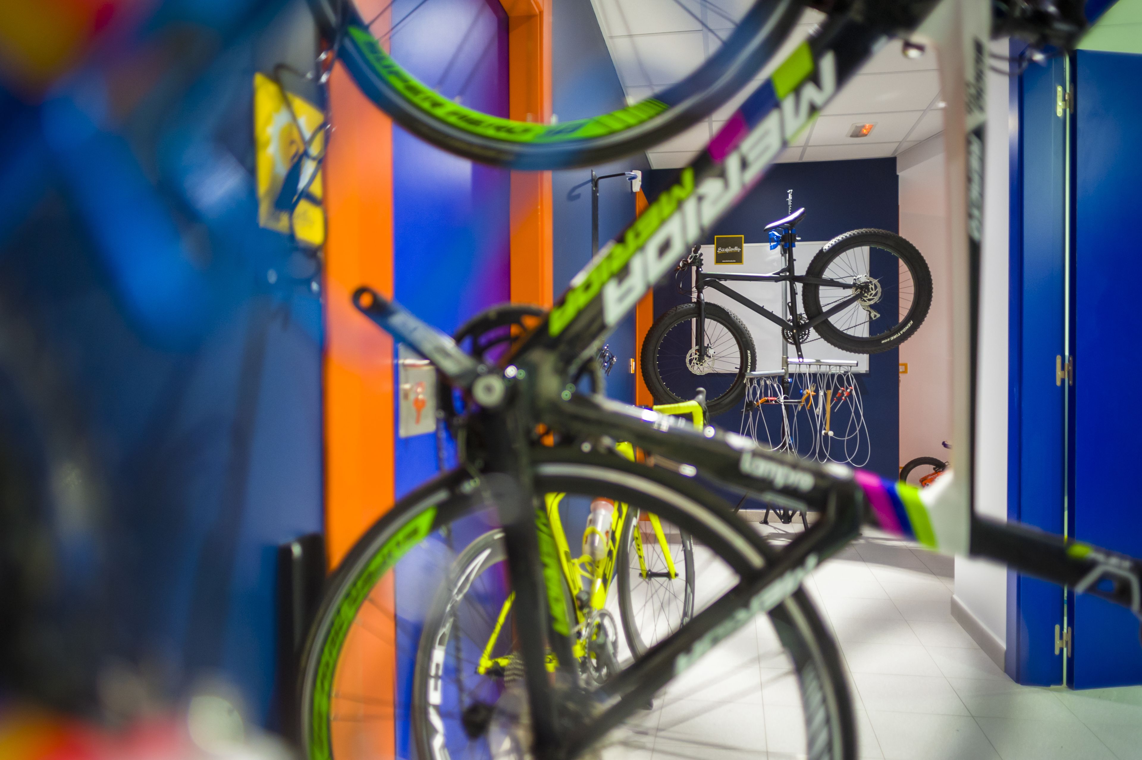 Ein Fahrrad in einer farbenfrohen Diele mit einer blauen Tür und einem Fahrradständer im Hintergrund.