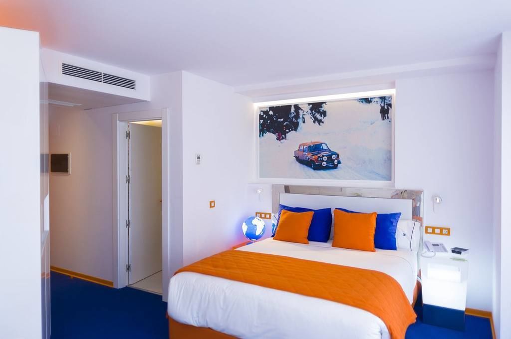 Hotellihuone, jossa on sänky, maapallo ja seinällä oleva maalaus, jossa on kuvattuna auto.