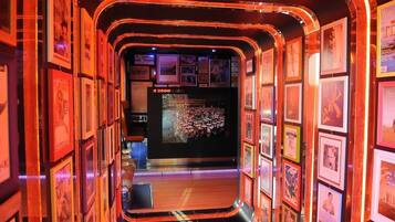 A corridor with framed pictures on the walls, a central display, and a small seating area.