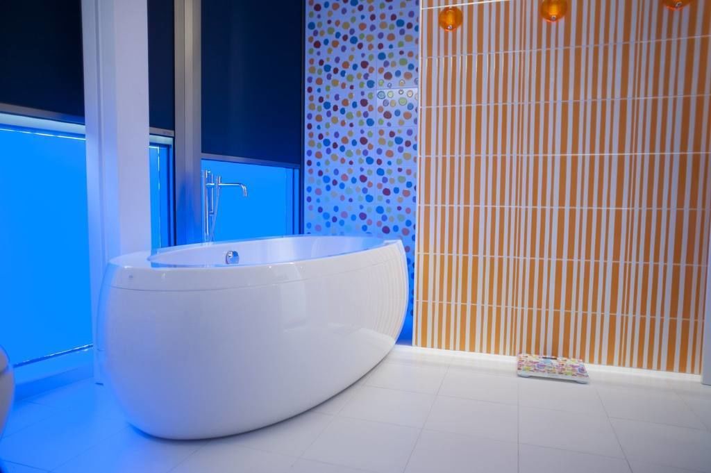 A modern bathroom with a large oval bathtub, a blue wall, and a striped pattern wall.