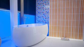 A modern bathroom with a large oval bathtub, a blue wall, and a striped pattern wall.