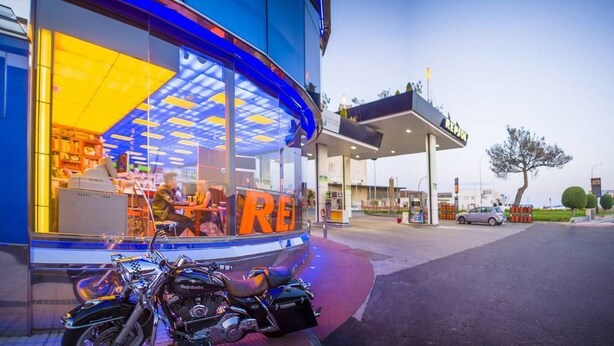 Una motocicleta estacionada frente a una tienda con mucha luz y un gran letrero que dice 'RE'.