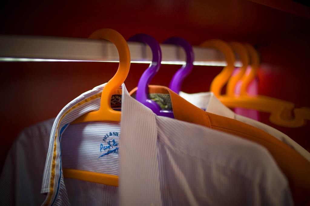 A row of colorful hangers on a closet rod.