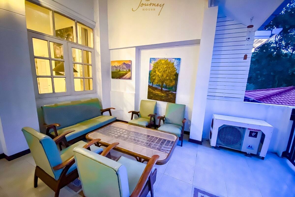 Un salon chaleureux avec un canapé, des fauteuils, une table basse et des œuvres d’art accrochées aux murs.