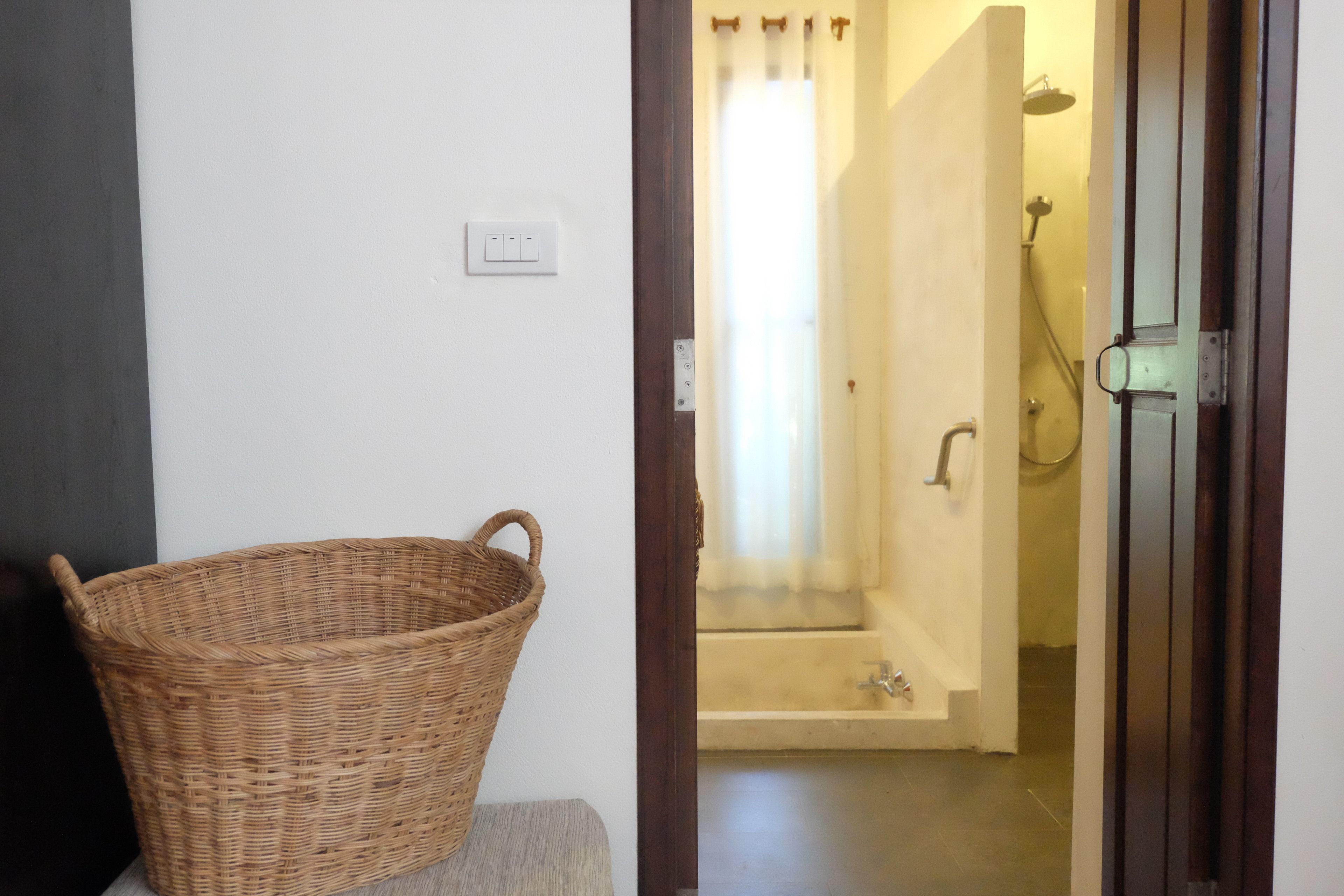 Un baño con ducha, bañera y una cesta de mimbre sobre un banco.