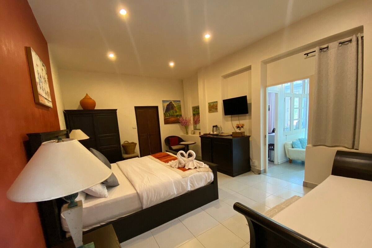 Une chambre d’hôtel équipée d’un lit, d’une table de chevet, d’une lampe, d’une télévision, d’un bureau et offrant une vue sur l’extérieur.