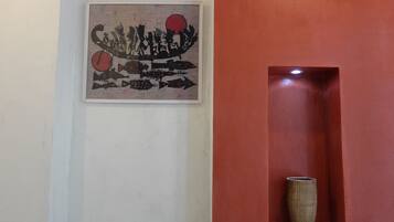 A framed artwork with abstract fish and a red circle on a white wall.