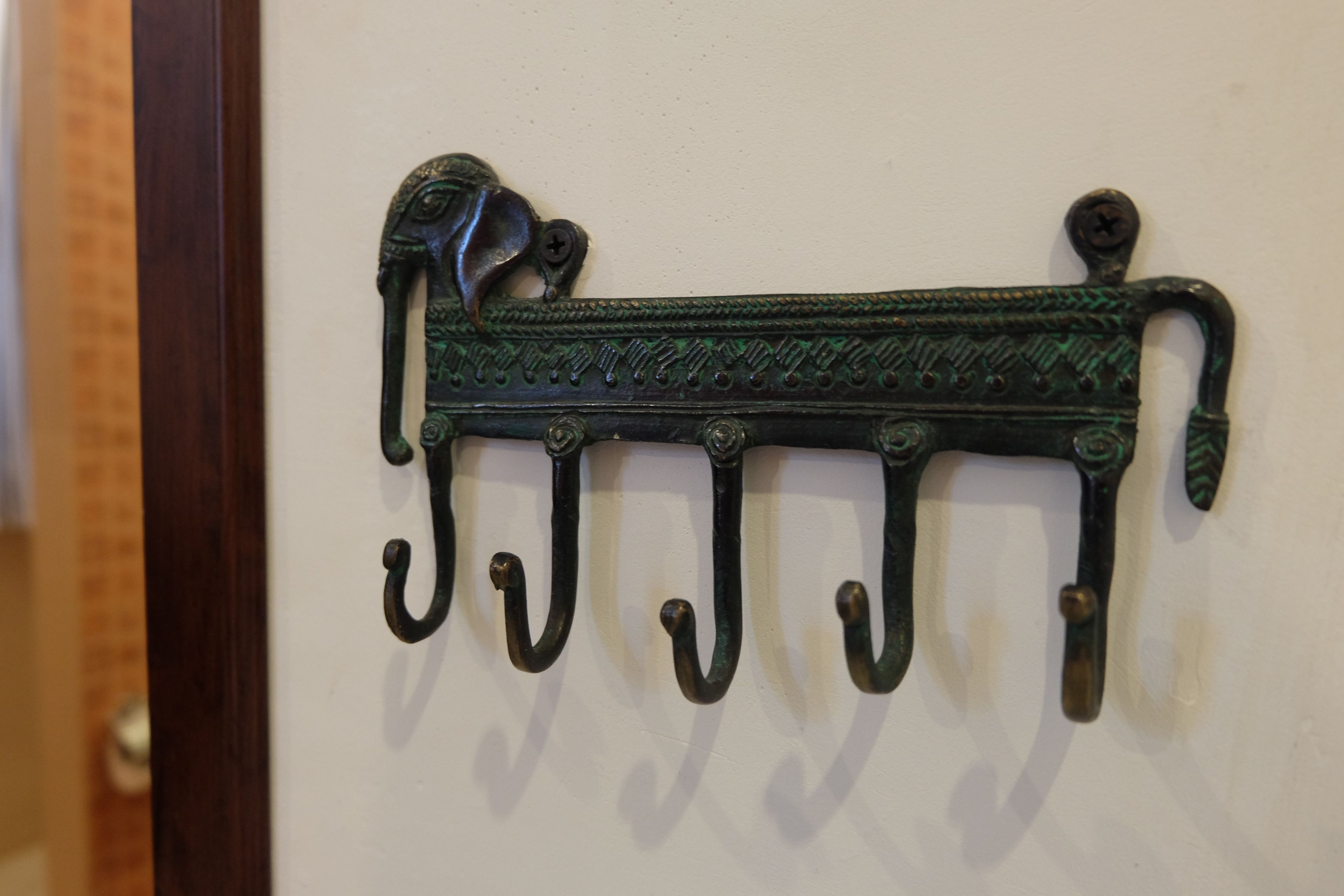 Um gancho de metal fixado na parede, com um detalhe decorativo no cabo.