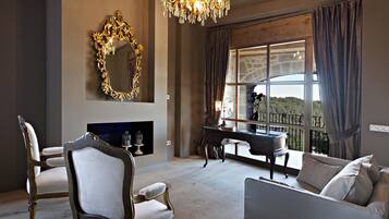 A living room with a large mirror, a chandelier, a fireplace, and a view of the outdoors.