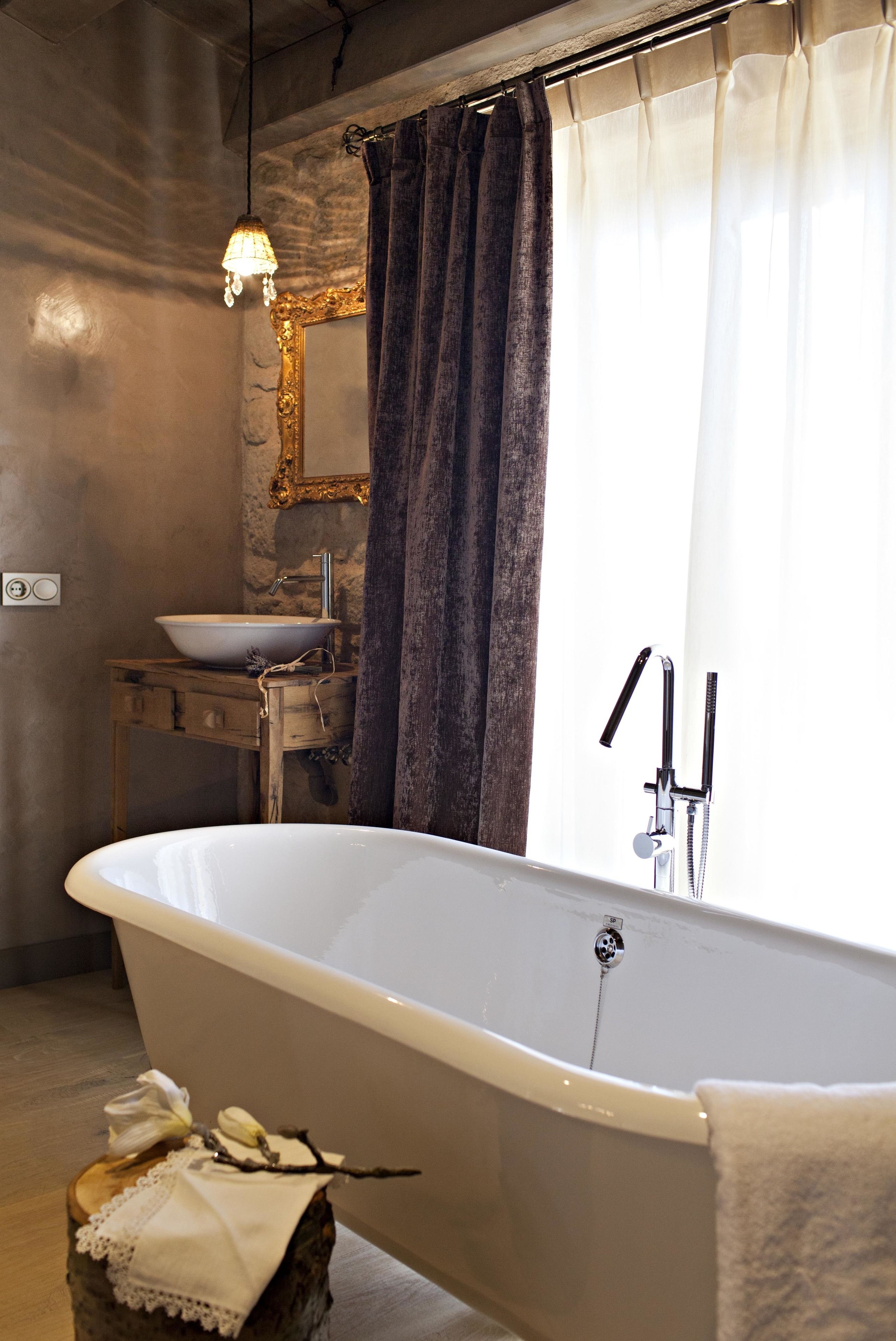 Un baño con una bañera independiente, un lavamanos con un lavabo, un espejo con un marco decorativo y un cabezal de ducha.