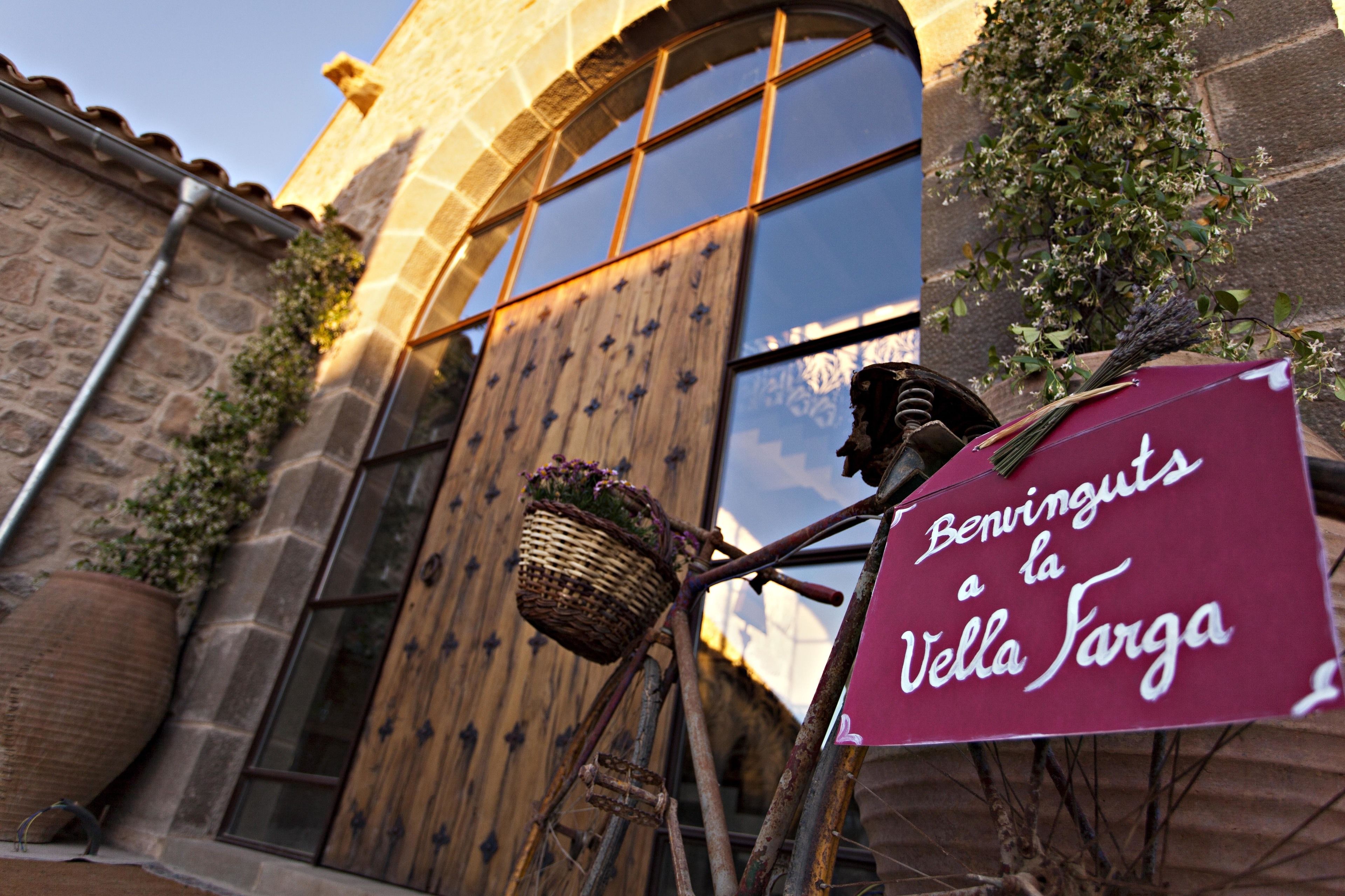 Un edificio rústico con una puerta de madera y un letrero que dice "Benvinguts a la Vella Sarga".