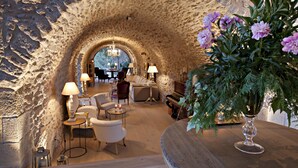 A cozy lounge area with a stone archway, comfortable seating, and a piano. - Hotel La Vella Farga (Lladurs)