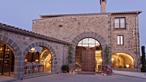 A stone building with arched doorways, a large wooden door, and a bicycle parked outside. - Hotel La Vella Farga (Lladurs)