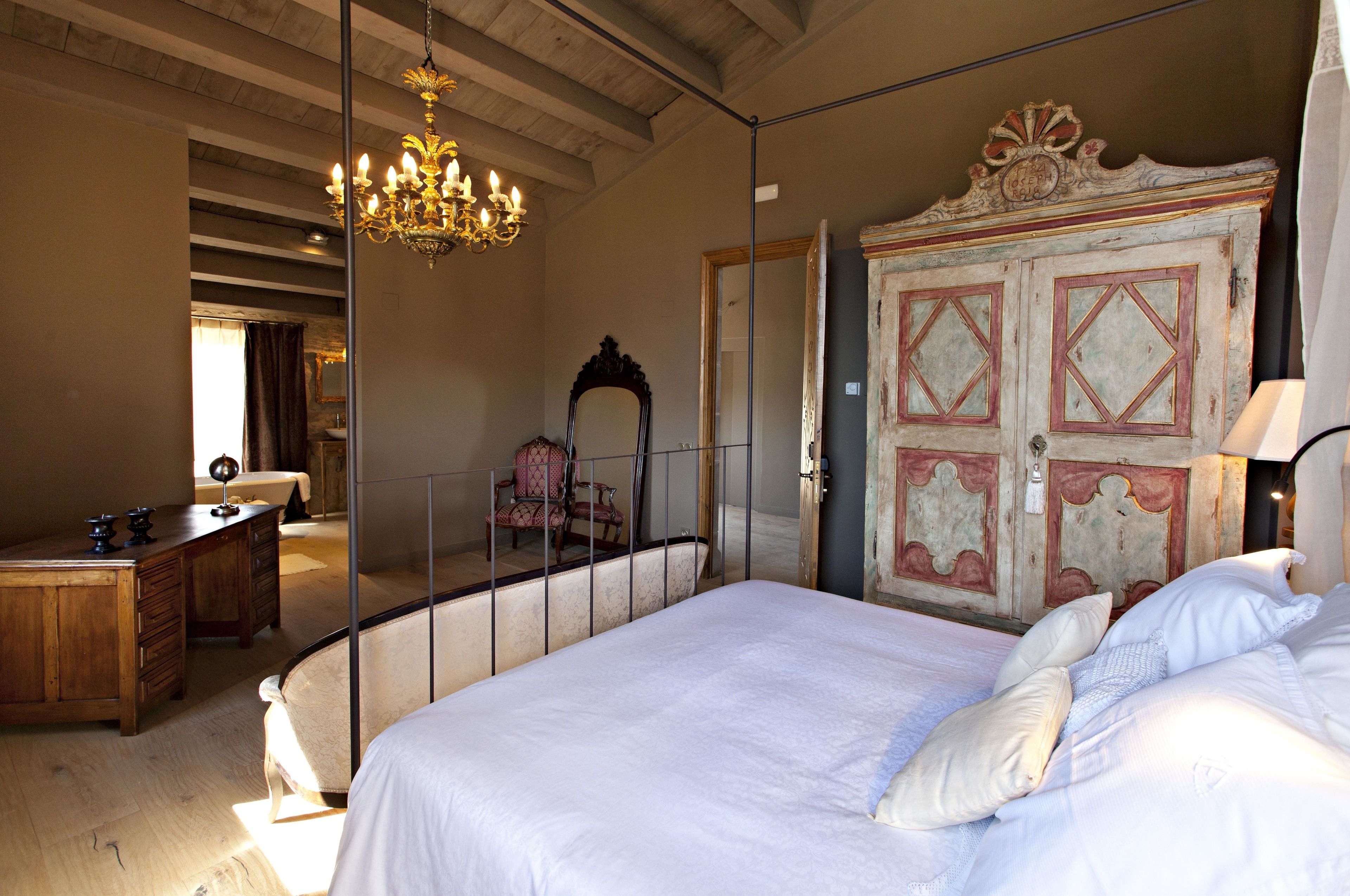 Un dormitorio con una cama grande, un aparador de madera, un escritorio, una silla y una araña.