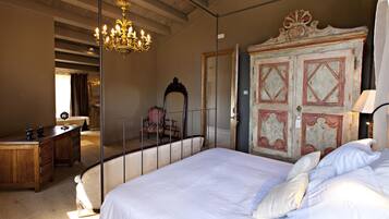 Un dormitorio con una cama grande, un aparador de madera, un escritorio, una silla y una araña.