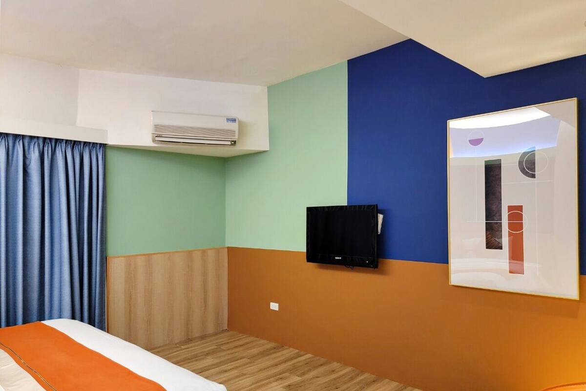 Quarto de hotel com cama, ar condicionado, televisão e espelho.
