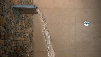 A spa area with a stone wall, a water feature, and a tiled floor.