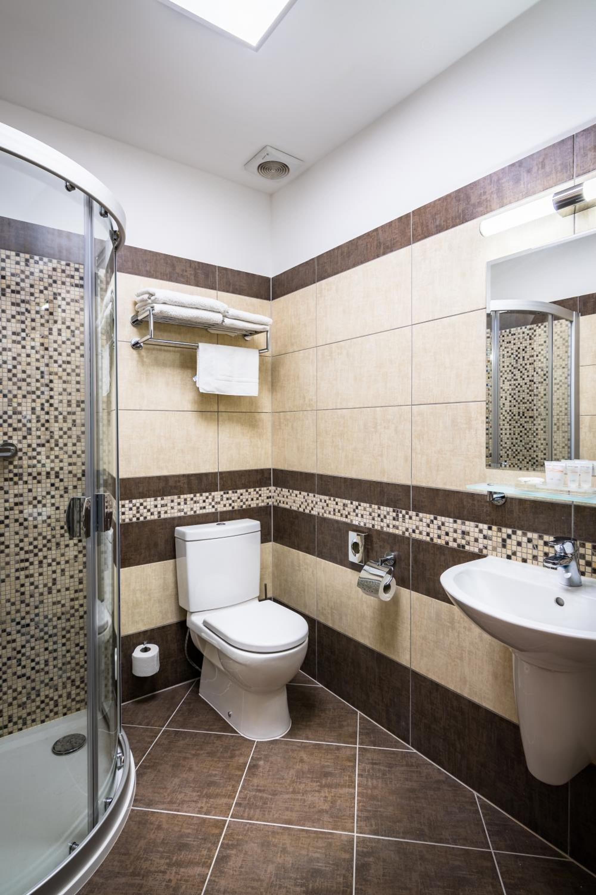 Une salle de bain moderne avec une douche à parois de verre, des toilettes, un lavabo et un miroir.