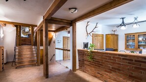 Un espace d’accueil avec un comptoir en briques, des poutres en bois et un escalier menant à une autre pièce.