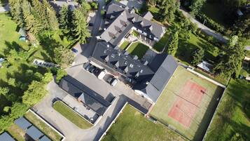 Vista aérea de un barrio residencial con varias casas, una cancha de tenis y un estacionamiento.