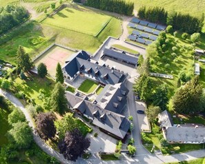 An aerial view of a property with a large building, multiple parking areas, and solar panels. - Holzberg (Svetla Hora)