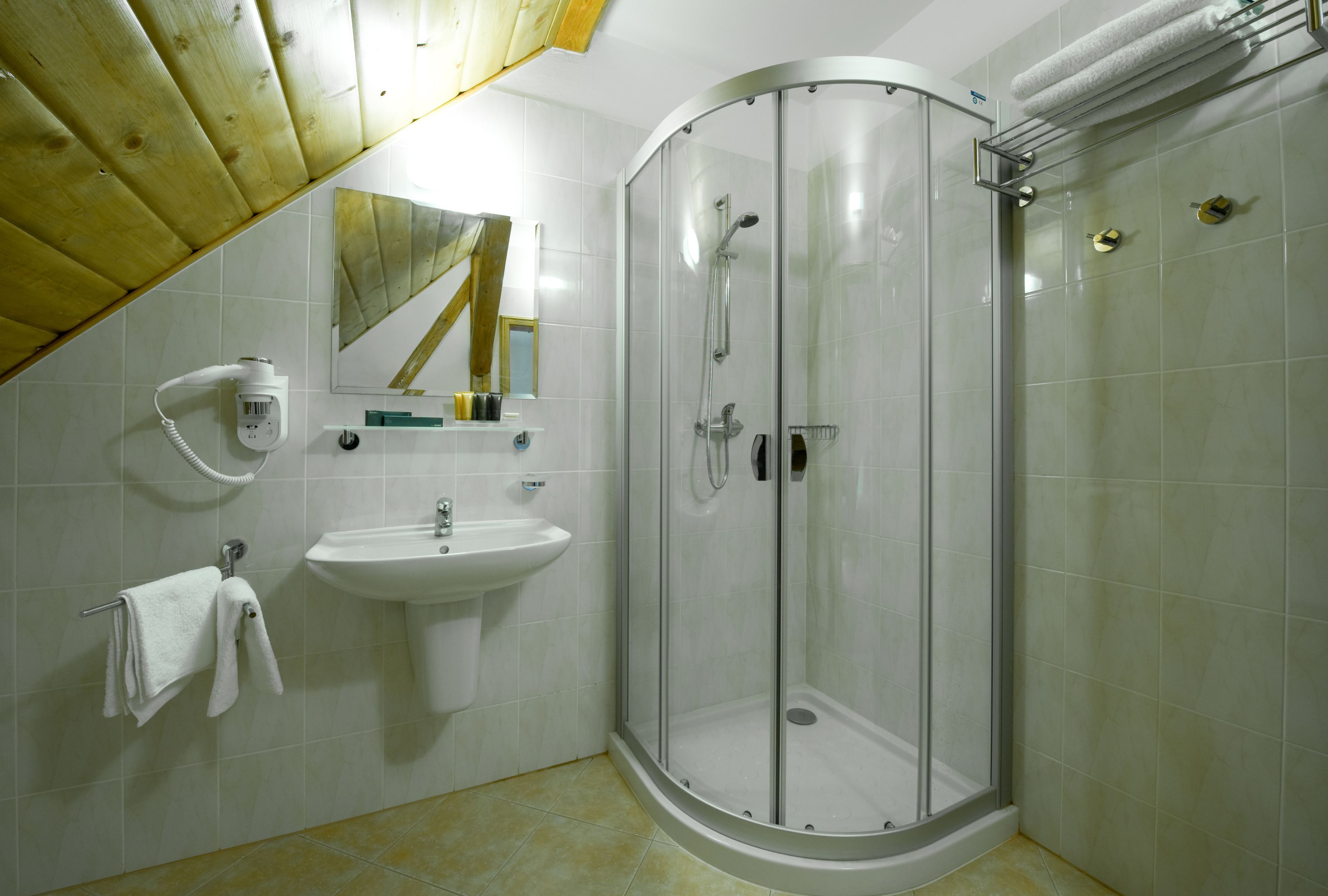 A bathroom with a glass-enclosed shower, a sink, and a towel rack.