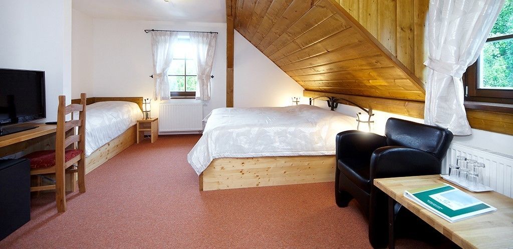 A bedroom with a bunk bed, a desk with a chair, a television, and a window with curtains.