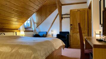 A cozy attic bedroom with a large bed, a desk, and a chair.