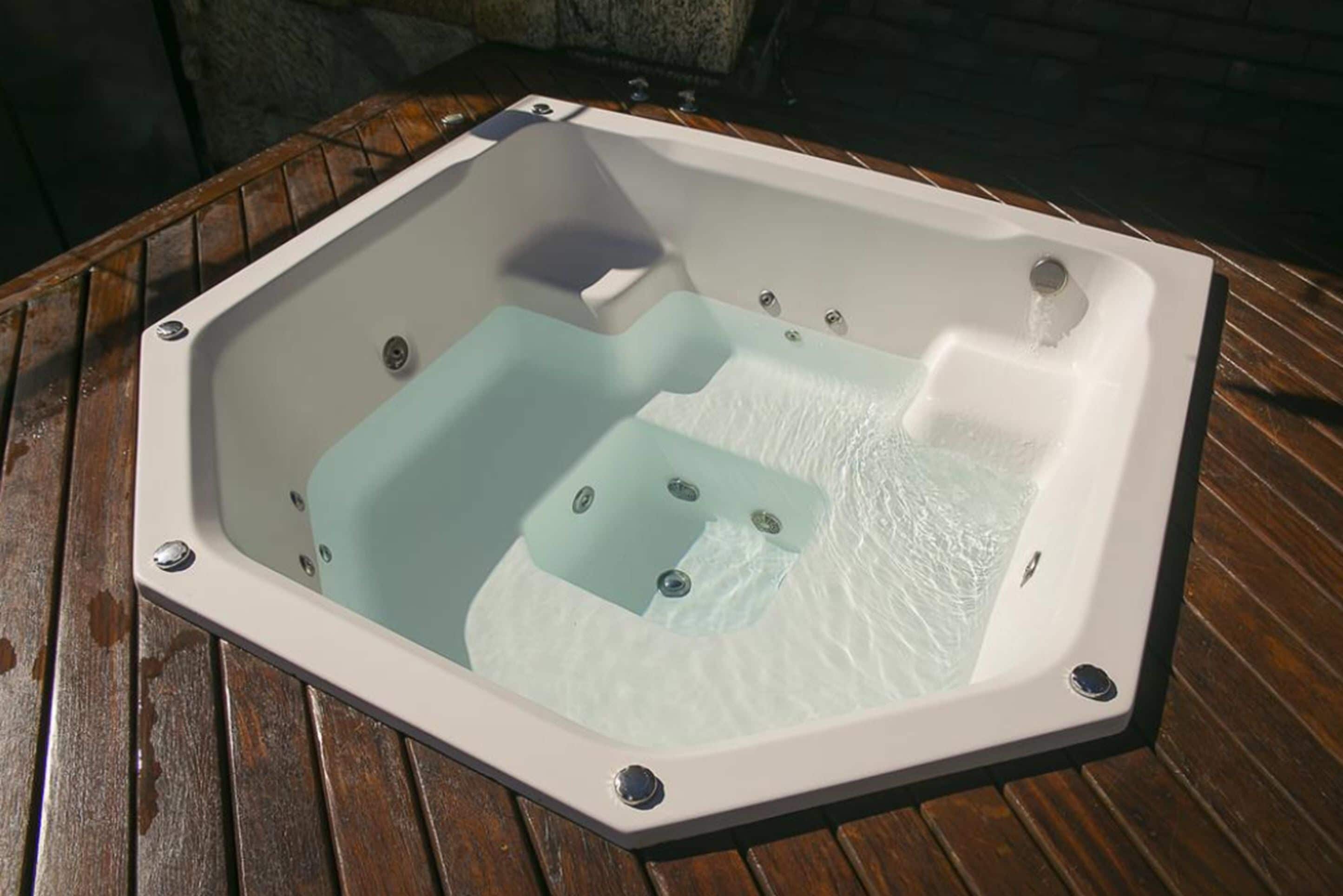 A square hot tub with a glass bottom, placed on a wooden deck.