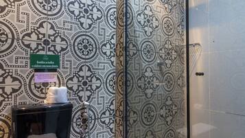 Ein Badezimmer mit gemusterten Fliesen, einer Duschkabine aus Glas und einem WC mit Handtuch.