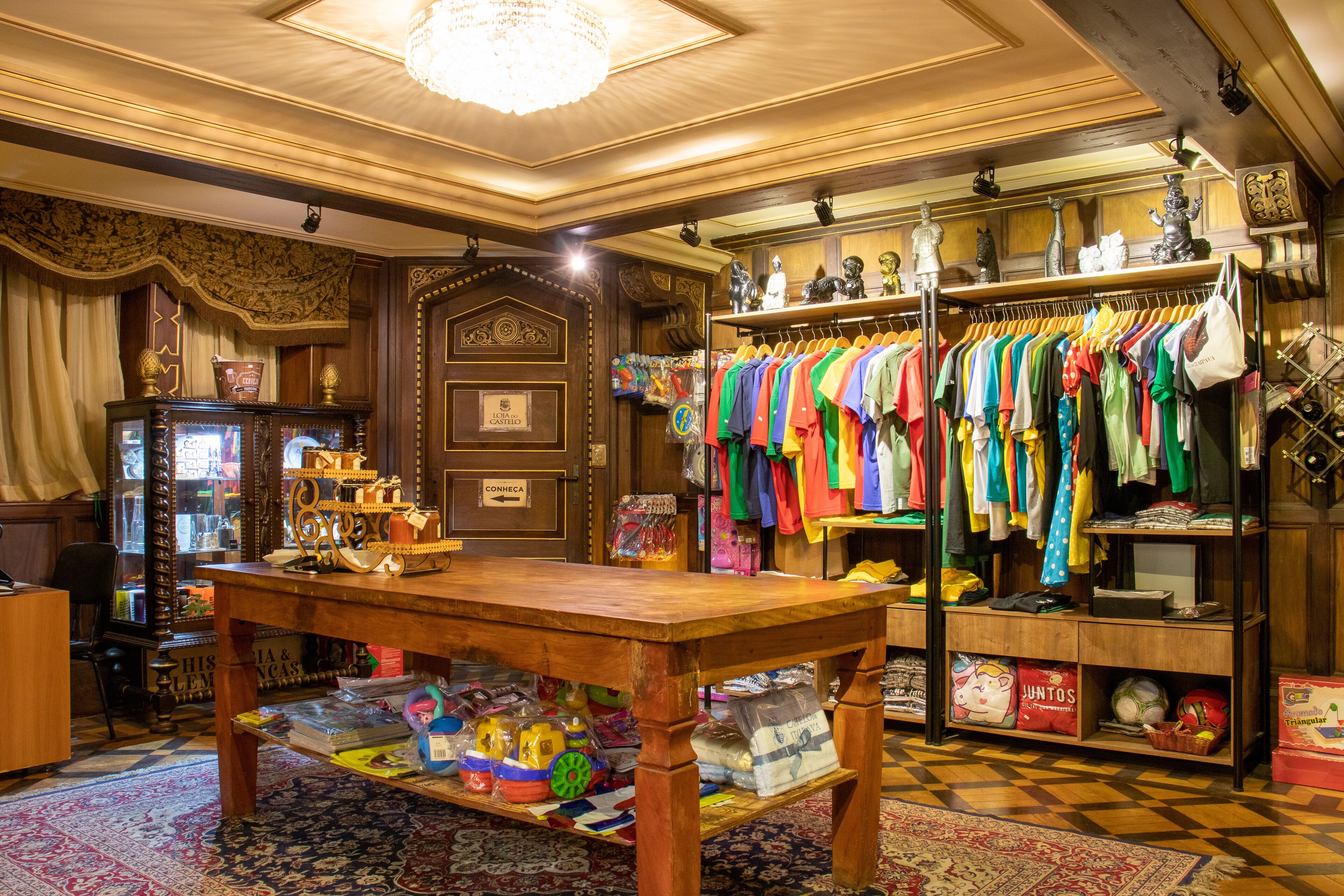 Habitación de hotel boutique con una mesa de madera, un perchero con ropa de colores y una alfombra estampada.