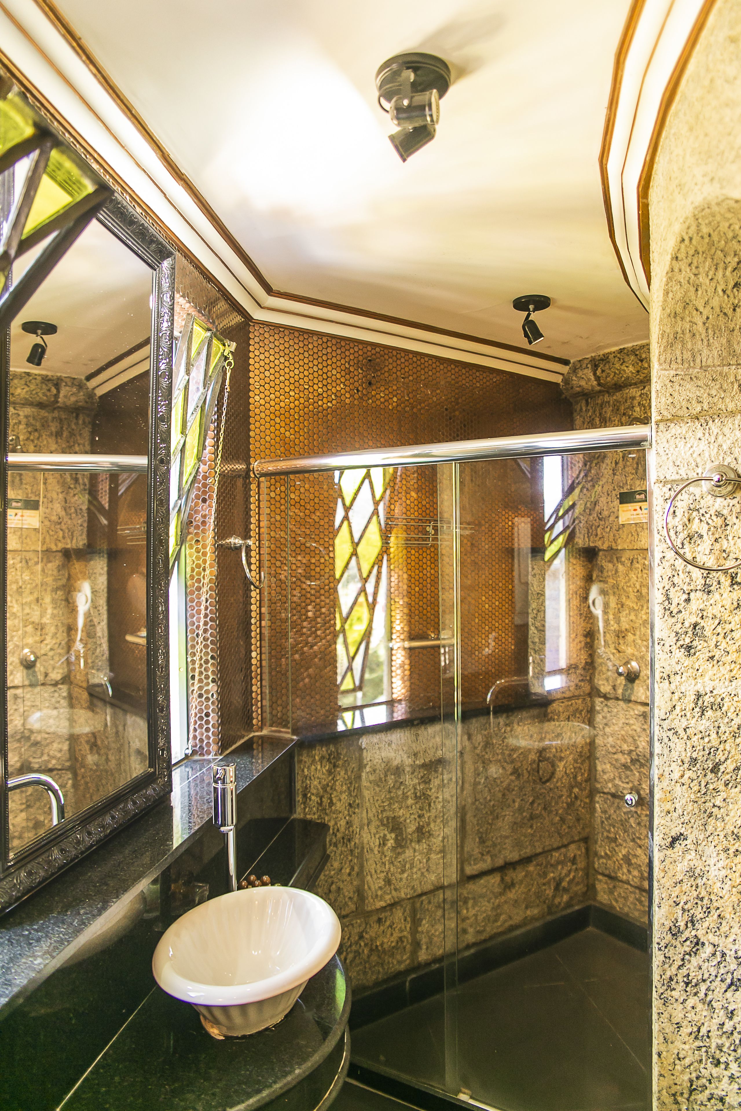 A modern bathroom with a glass-enclosed shower, a marble sink, and a large mirror.